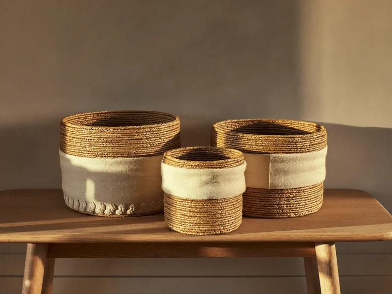 Tre ceste in seagrass e tessuto di misure diverse su una panca in rovere chiaro